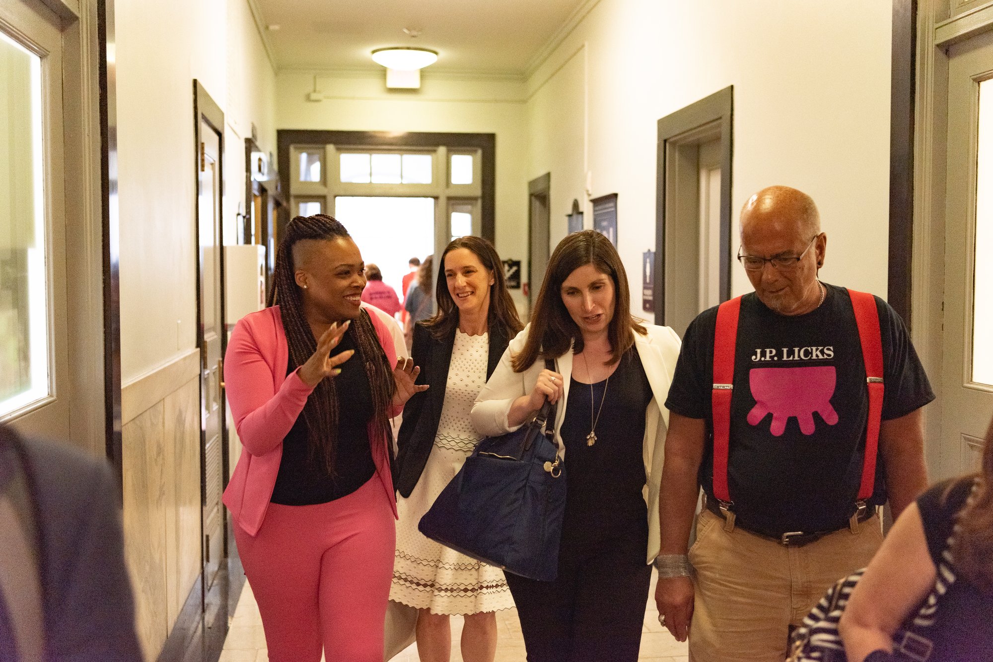 Rica Elysée talking with fellow attendees while walking down a hallway
