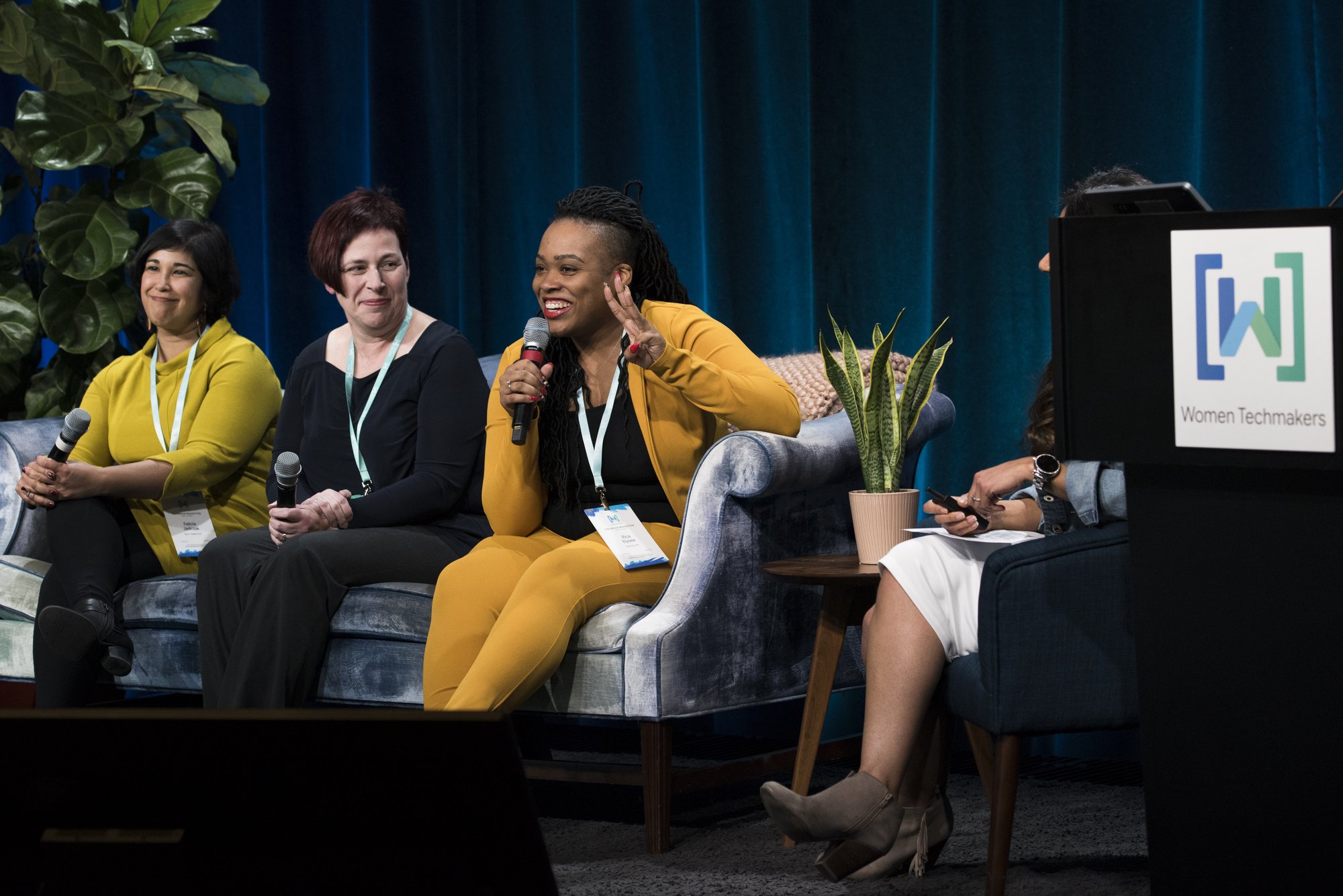 Rica Elysée speaking into a microphone on a panel at a Women Techmakers event